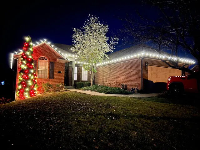 Christmas roofline lights and a decorated tree beside a brick home