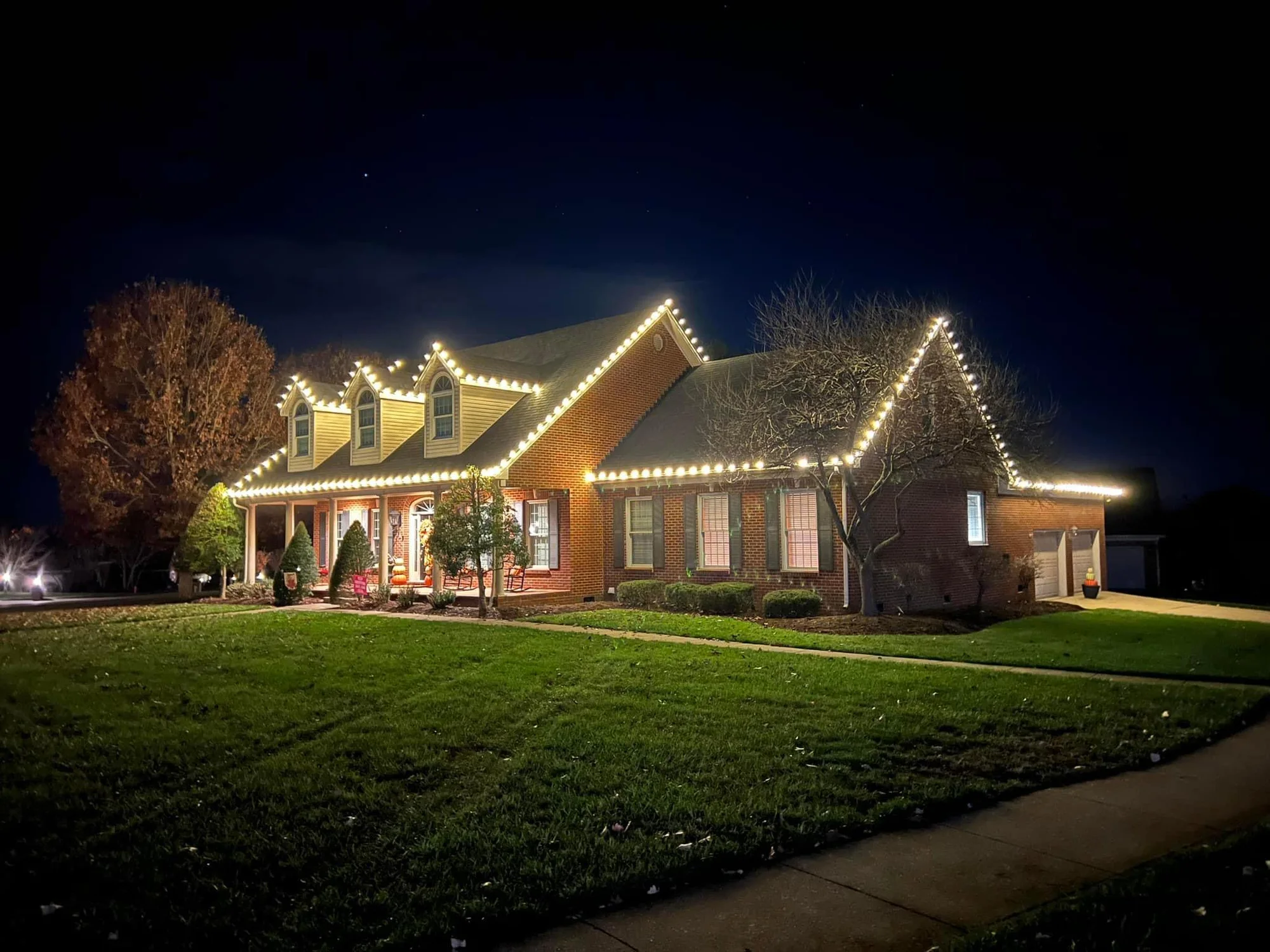 Warm white Christmas lights outlining the peaks of a brick home