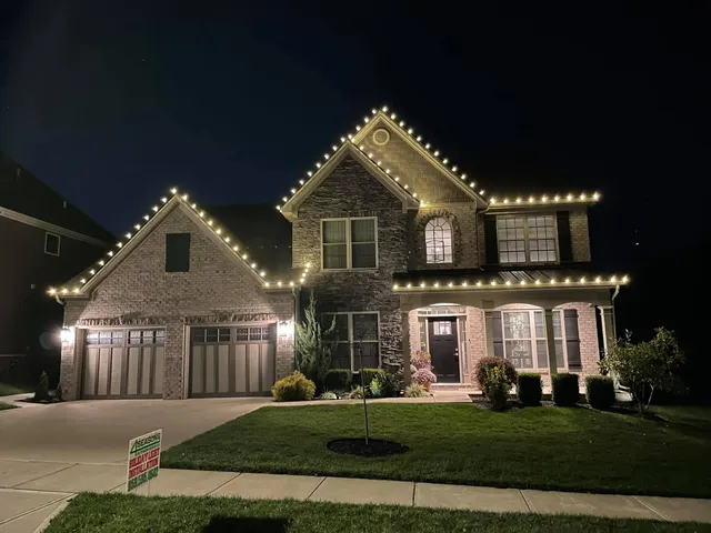 White Christmas lights outlining a two-story home and garage