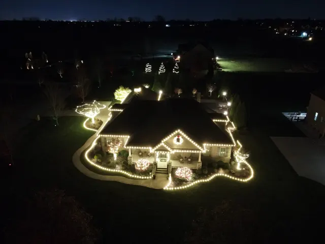 Aerial view of roofline, garden-edge and tree lights around a home