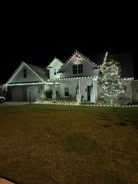 White roofline lights and a glowing tree beside a home