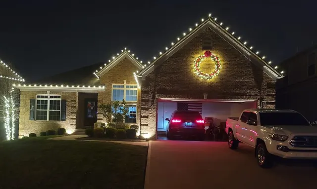 Illuminated wreath and roofline lights above a garage