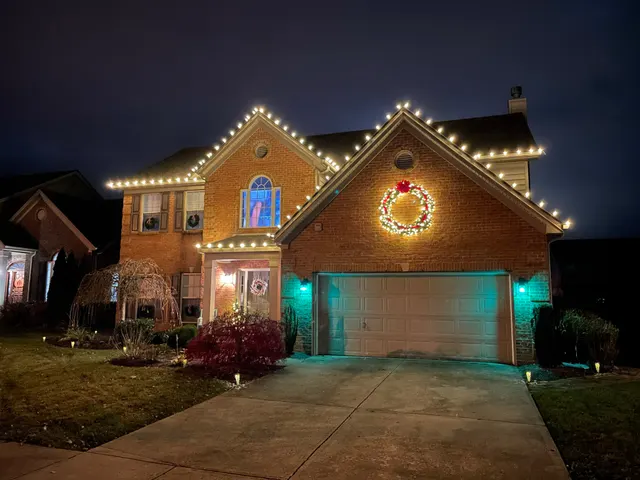 Holiday wreaths and roofline lights on a brick home