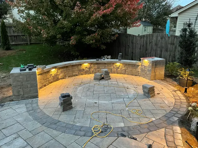 Curved patio wall illuminated by warm landscape lights