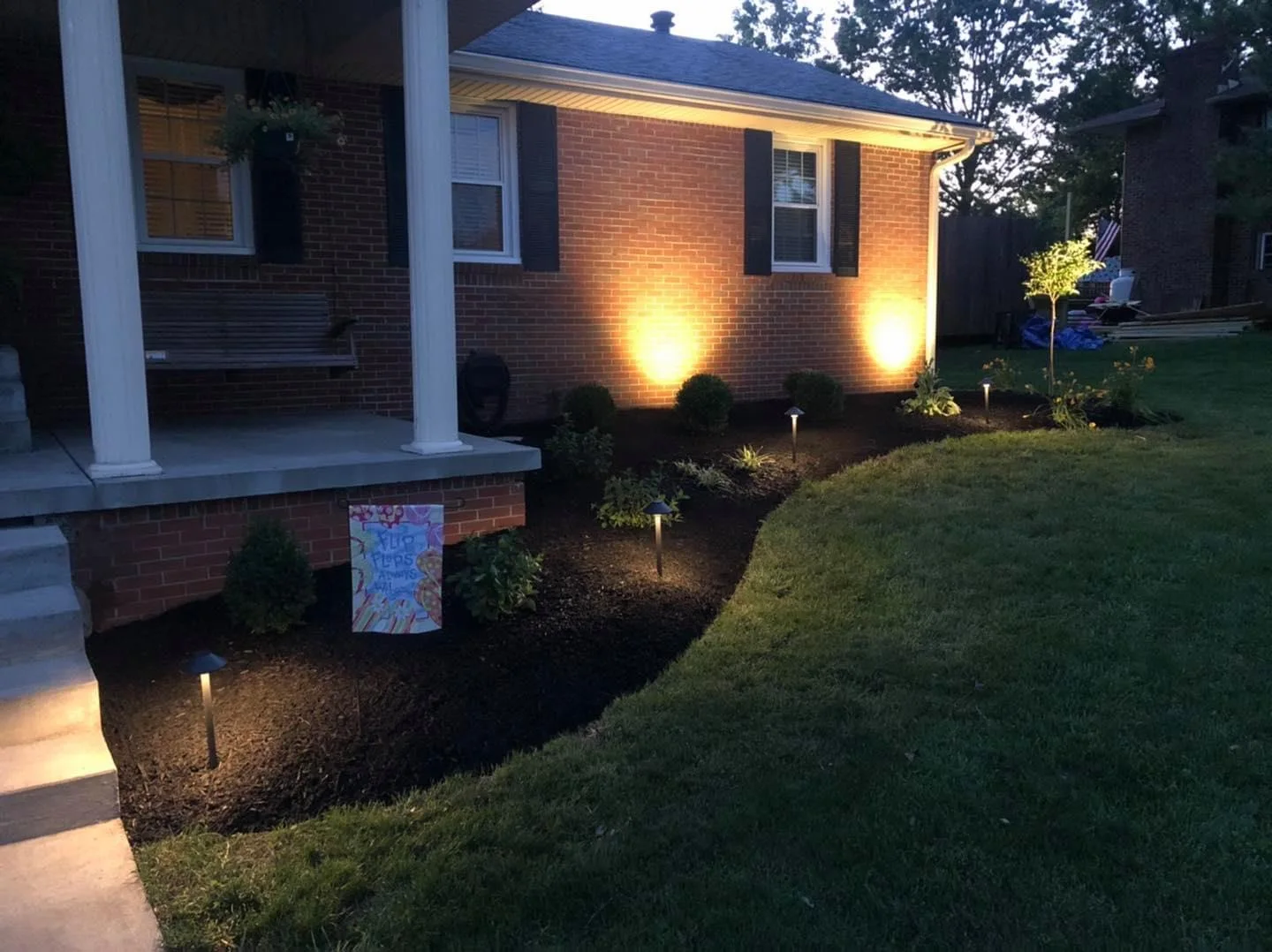 Landscape lighting highlighting a brick entry and planting bed