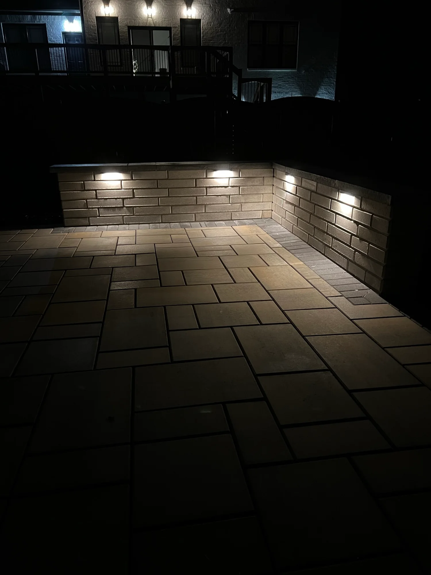 Nighttime view of a paver patio and illuminated seating walls
