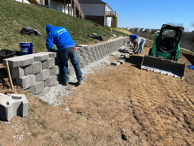 Crew building a segmental retaining wall on a slope