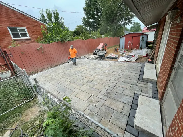 Patio construction beside a brick home and wood fence